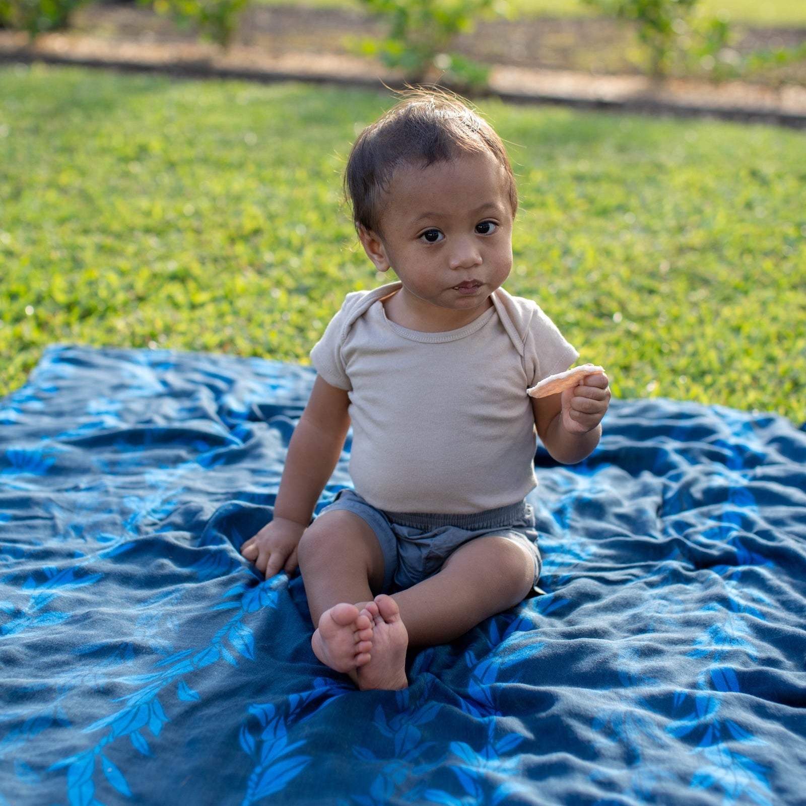 Child sitting on a blue blanket in a garden