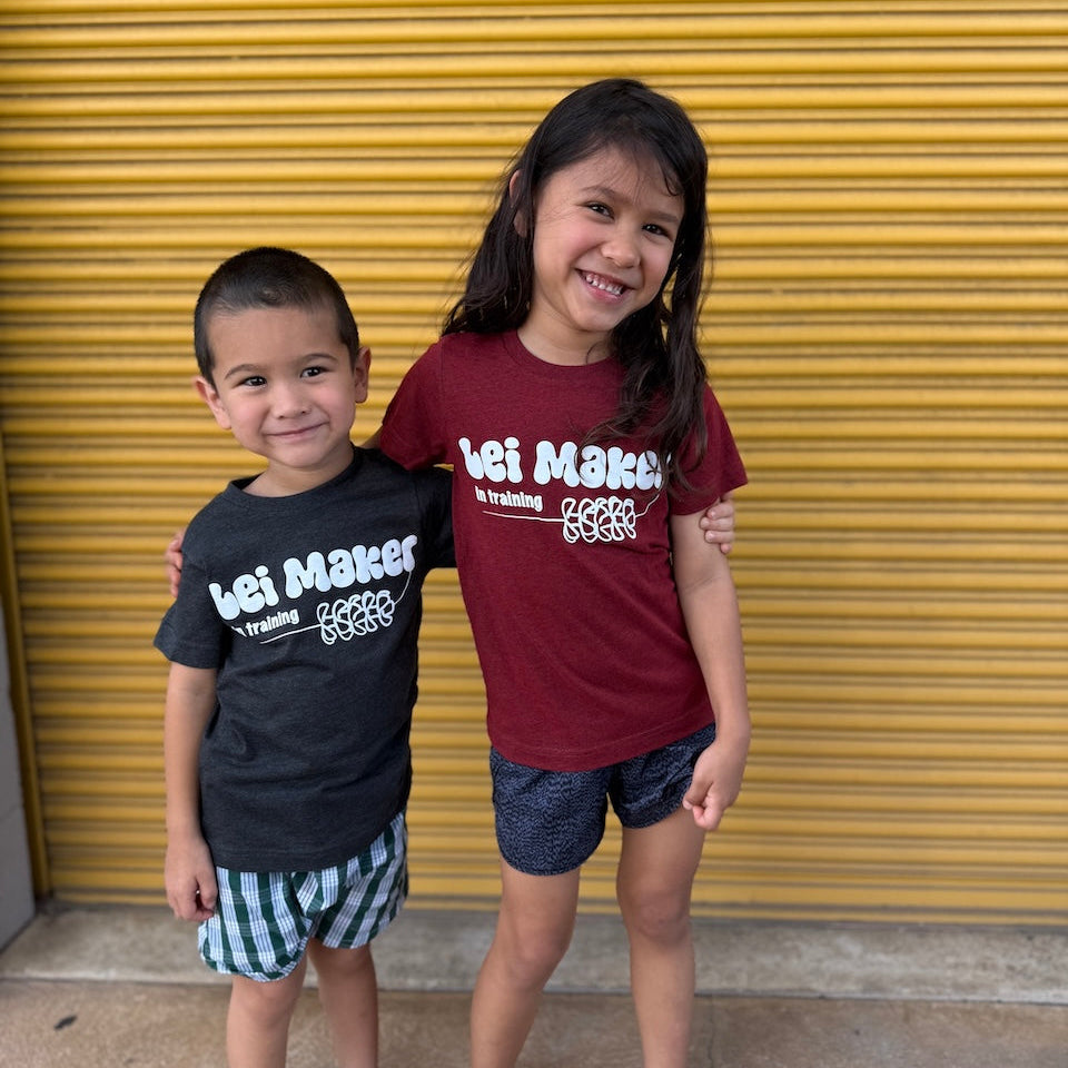 Two children wearing matching shirts in front of a yellow garage door.