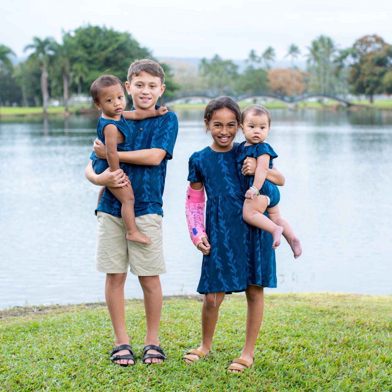 Four children standing on grass by the water