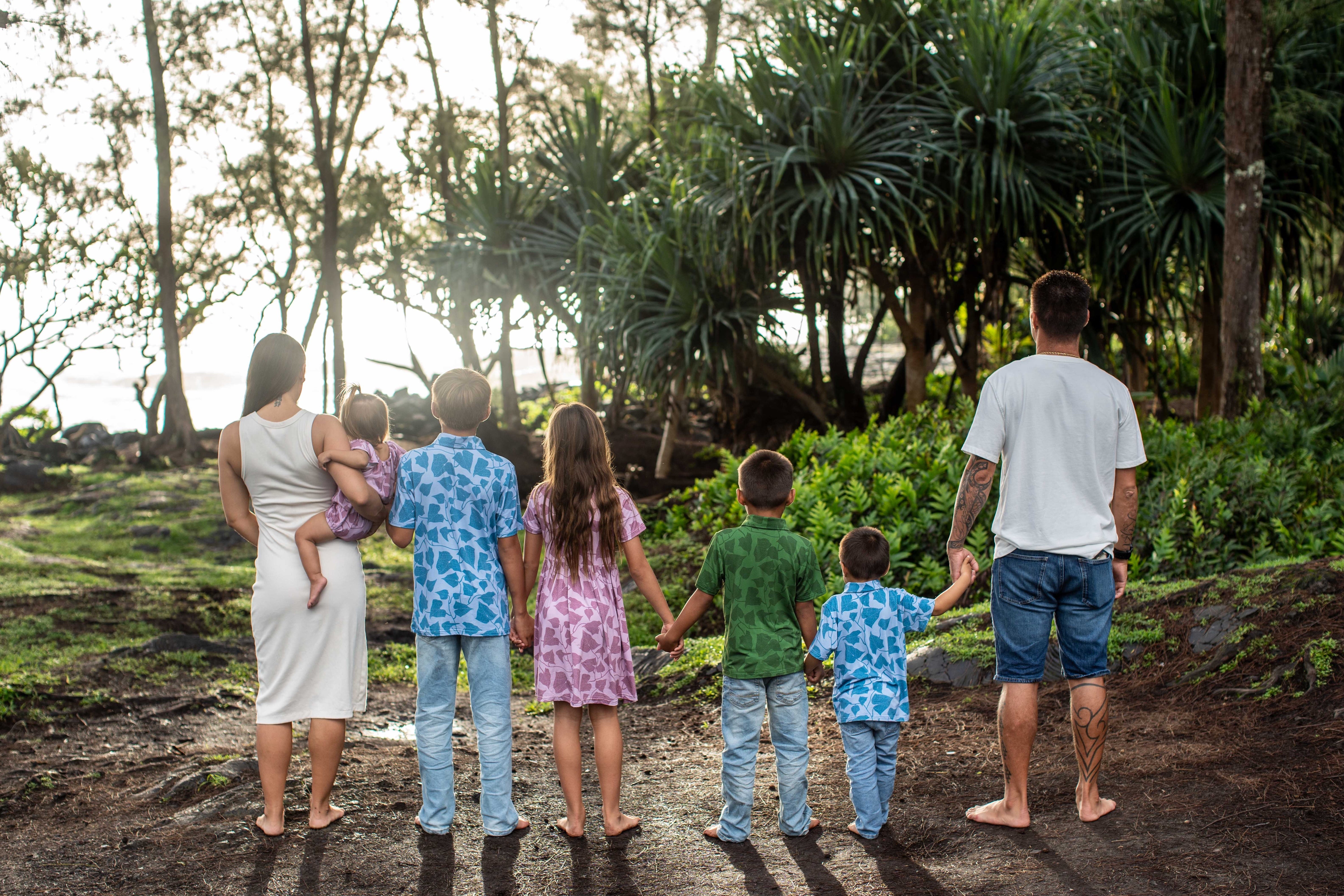family wearing peʻahi fern prints. girls are in pink, boys are in blue and green colorways.