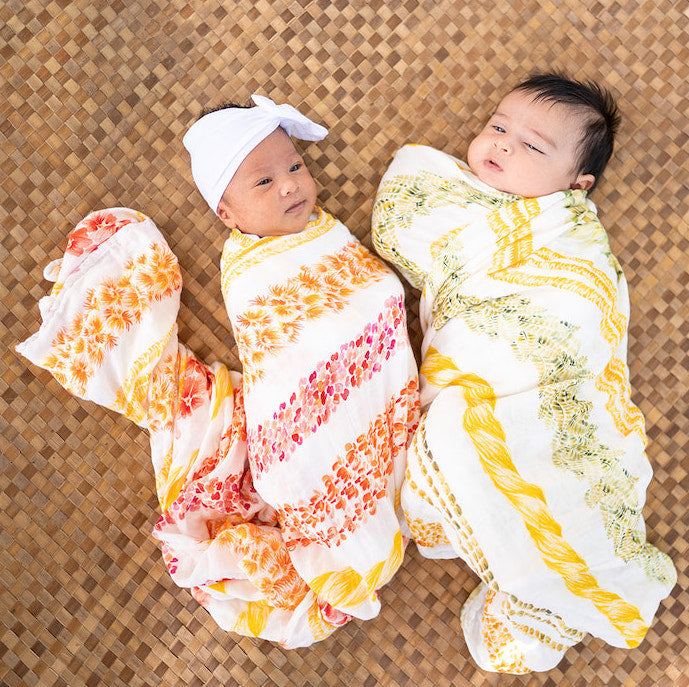 two newborns swaddled in lei alaula bamboo kapa moe